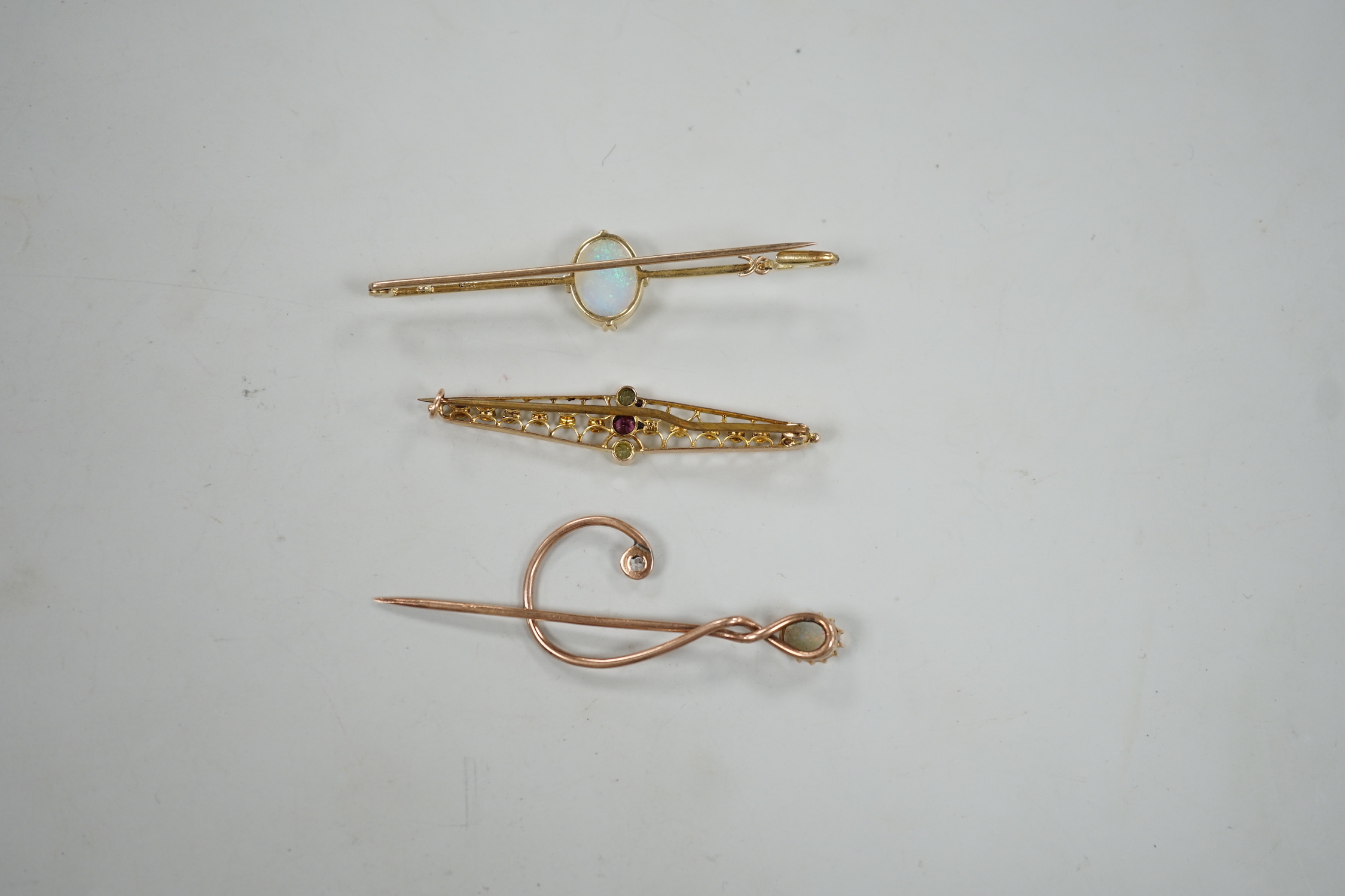 A novelty yellow metal, white opal and diamond set 'treble clef' stick pin, 60mm, a 15ct and white opal set bar brooch and one other 9ct and gem set brooch, gross weight 8.2 grams.